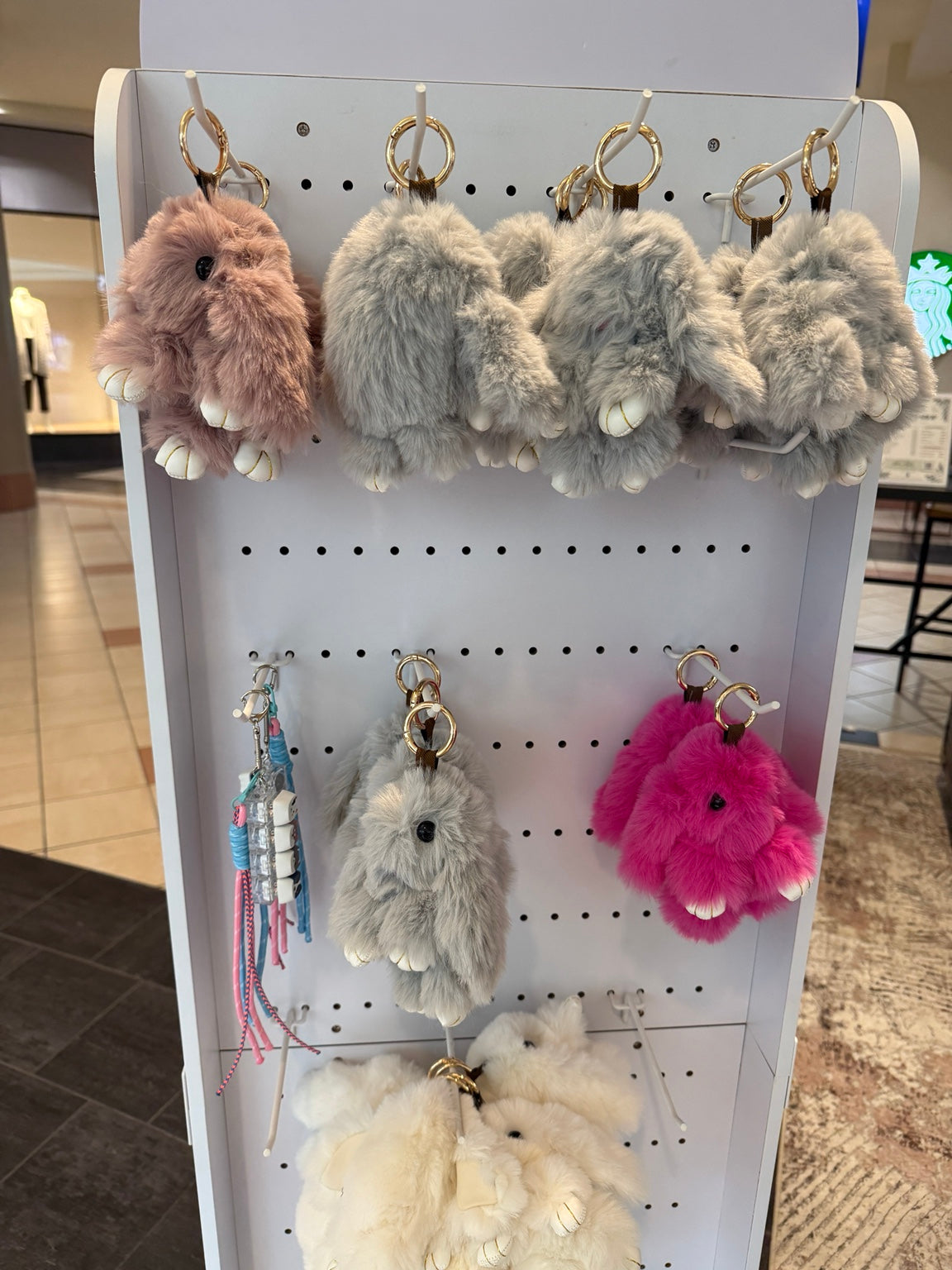 Fluffy bunny keychains in multiple colors displayed at NeuroNest pop-up, original photograph