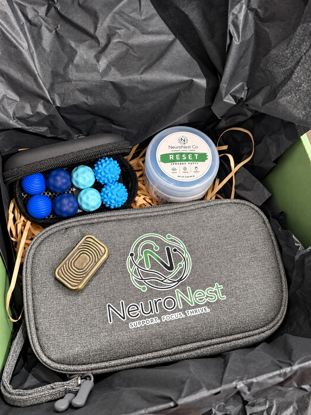 Completed NeuroNest adult fidget gift box with one brass-look slider, one Reset Putty container, eight blue magnetic balls and one gray organizer